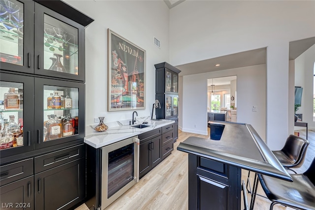 kitchen featuring a kitchen bar, sink, wine cooler, and light hardwood / wood-style flooring