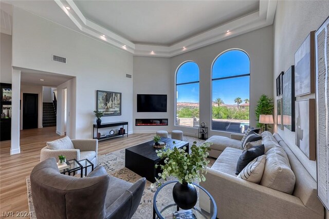 living room featuring a tray ceiling, a high ceiling, and hardwood / wood-style flooring