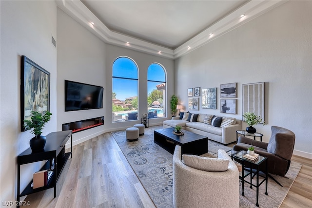 living room with a tray ceiling, a high ceiling, and hardwood / wood-style flooring