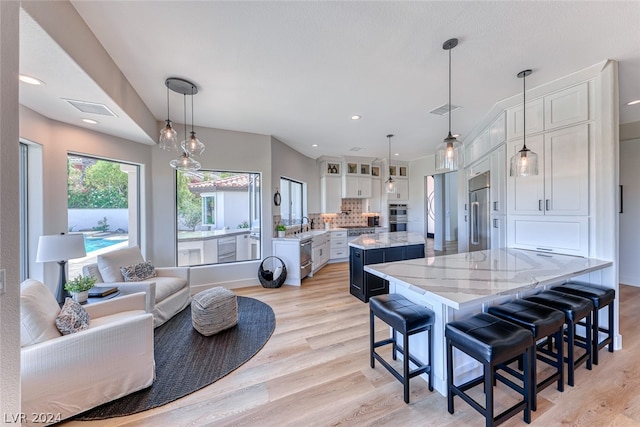 kitchen featuring light hardwood / wood-style flooring, white cabinets, tasteful backsplash, and pendant lighting