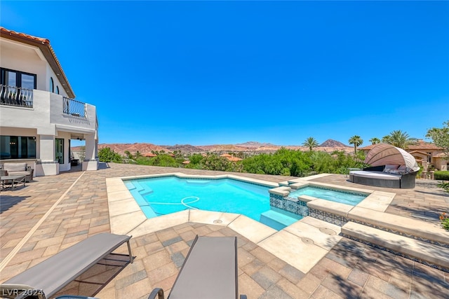 view of swimming pool featuring a mountain view, an in ground hot tub, and a patio