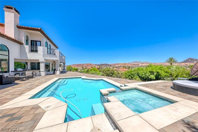 view of swimming pool with an in ground hot tub, a patio area, and a mountain view