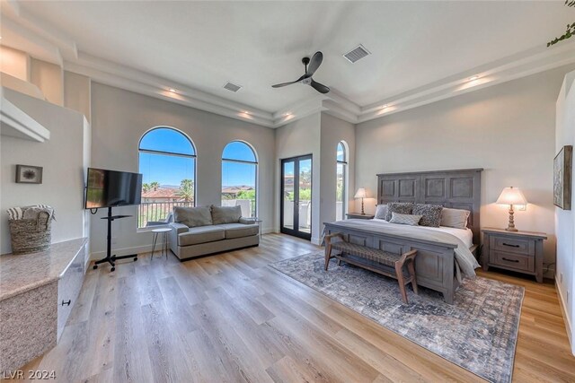 bedroom featuring a raised ceiling, ceiling fan, light hardwood / wood-style floors, and a high ceiling