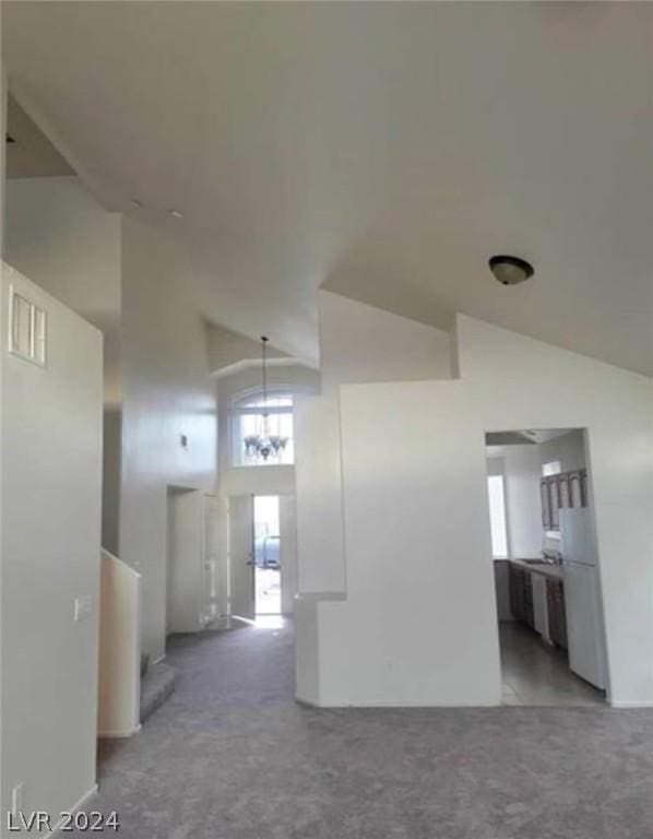 interior space featuring light carpet, a notable chandelier, and high vaulted ceiling