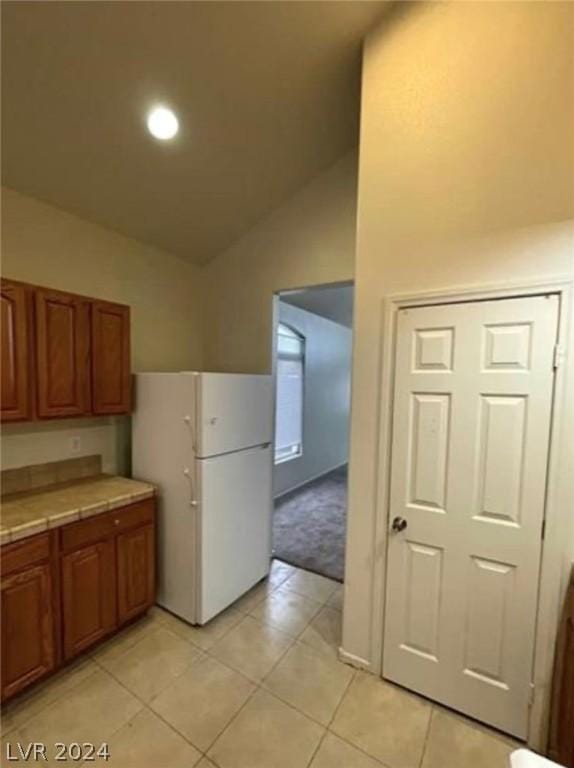 kitchen with light tile patterned floors, white refrigerator, and lofted ceiling