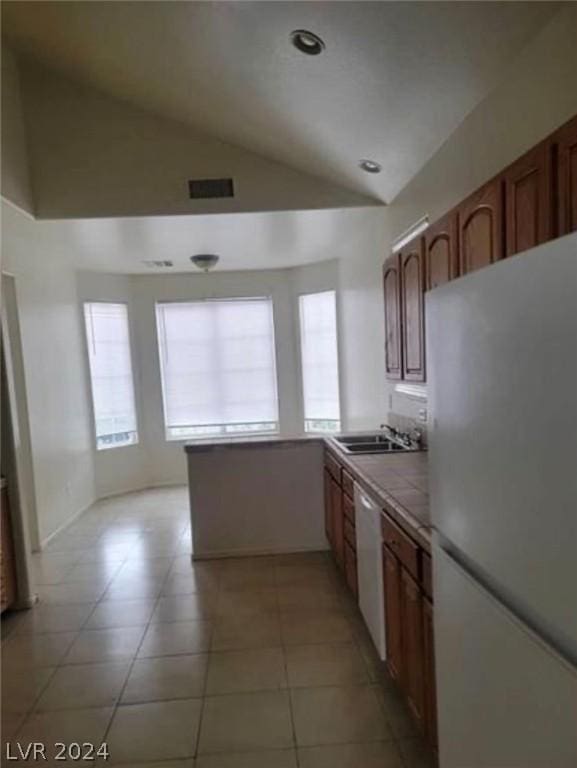 kitchen with lofted ceiling, sink, white appliances, tile counters, and light tile patterned floors