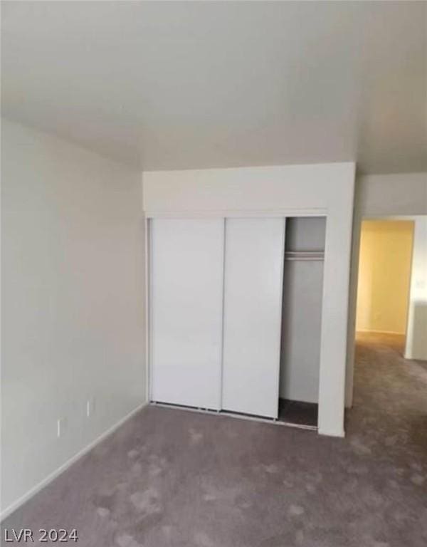 unfurnished bedroom featuring a closet and dark colored carpet