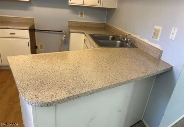 kitchen with white cabinets, kitchen peninsula, and sink