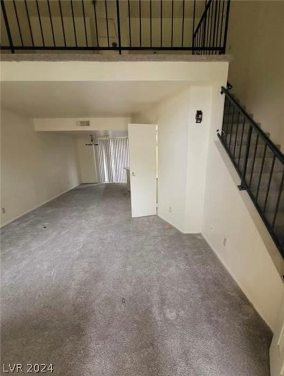 unfurnished living room featuring carpet and a high ceiling