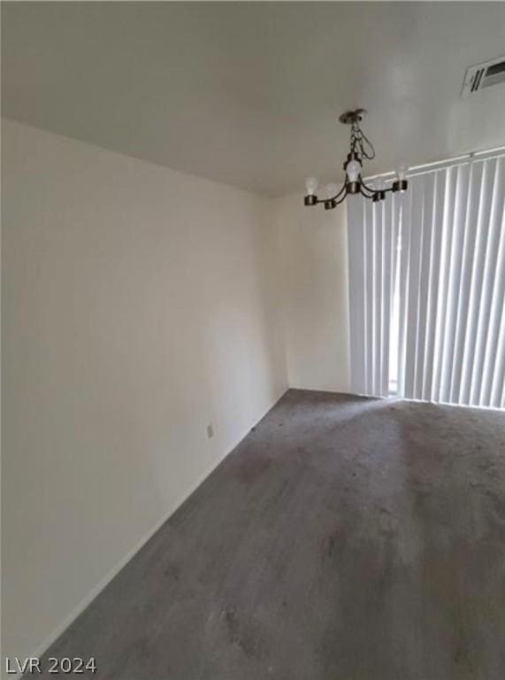 carpeted spare room featuring a notable chandelier