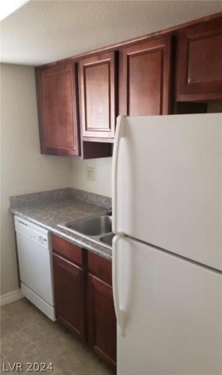 kitchen with light tile patterned flooring, white appliances, and sink