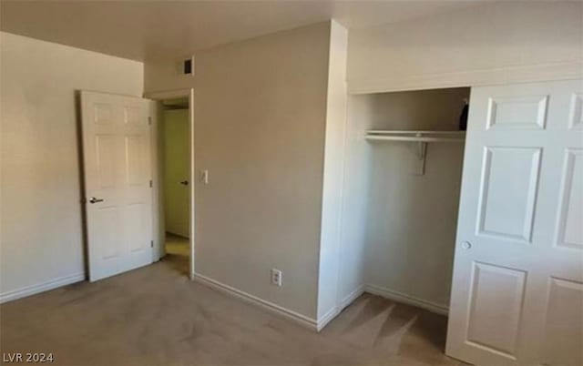 unfurnished bedroom featuring light carpet and a closet