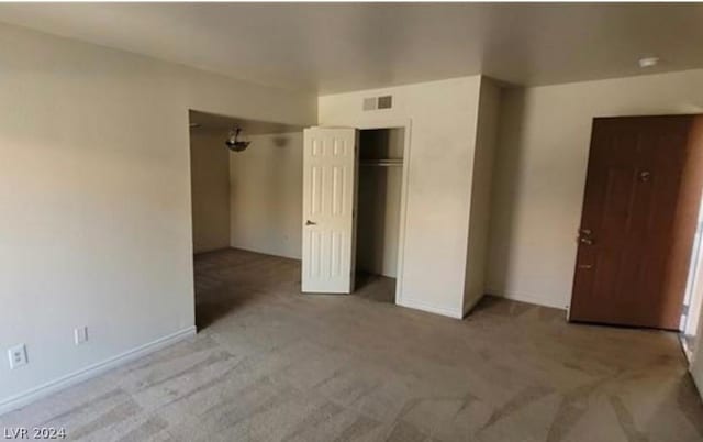 unfurnished bedroom with light colored carpet and a closet