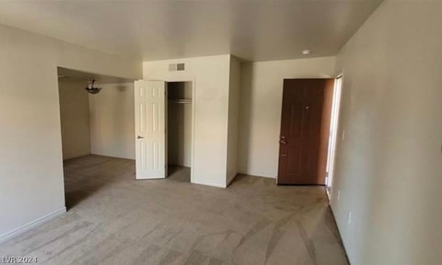 unfurnished bedroom featuring light colored carpet and a closet