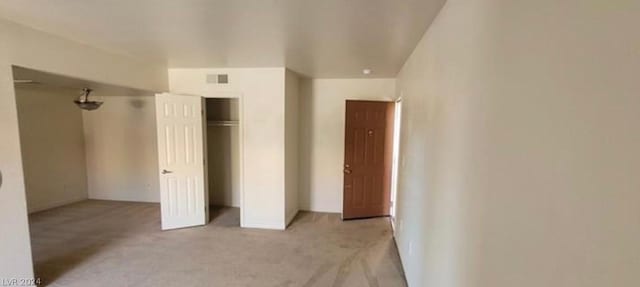 unfurnished bedroom with light carpet and a closet