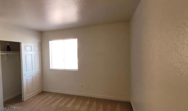 unfurnished bedroom featuring a closet and light colored carpet