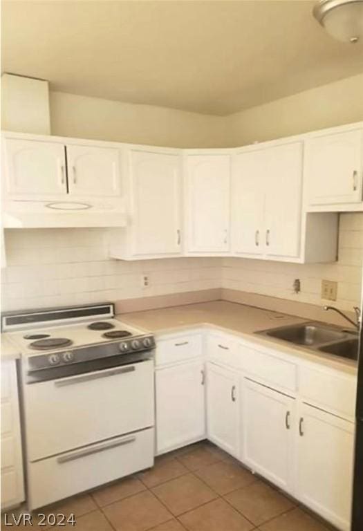 kitchen with dark tile patterned flooring, white cabinets, extractor fan, white range with electric cooktop, and sink