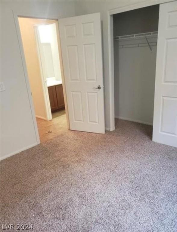 unfurnished bedroom with light colored carpet and a closet