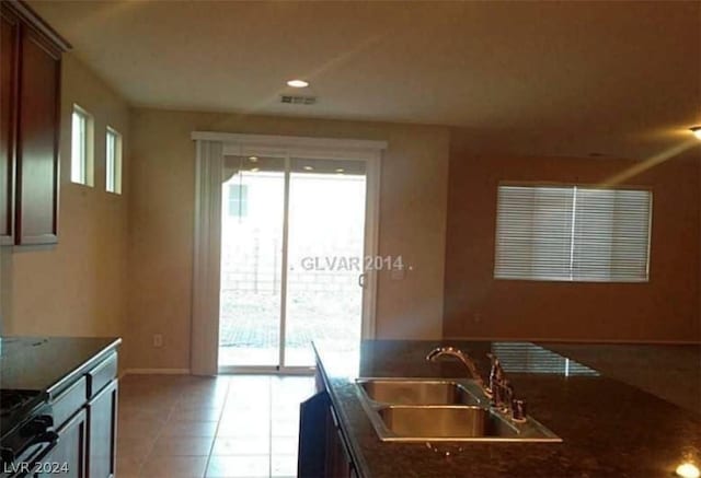 kitchen with light tile patterned flooring, sink, and dark stone countertops