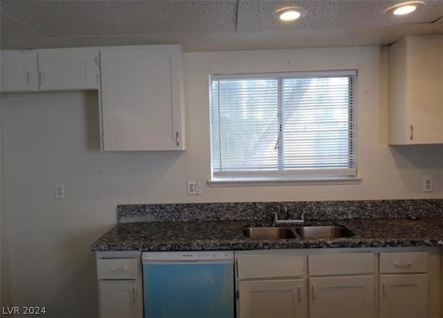 kitchen featuring dishwasher, sink, white cabinets, and dark stone counters