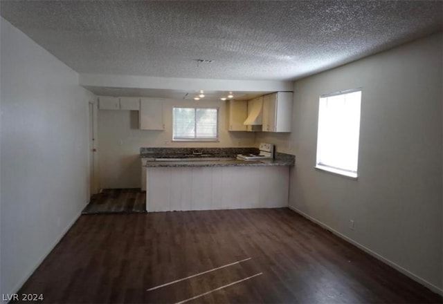 kitchen featuring stove, dark wood-type flooring, a wealth of natural light, and white cabinets