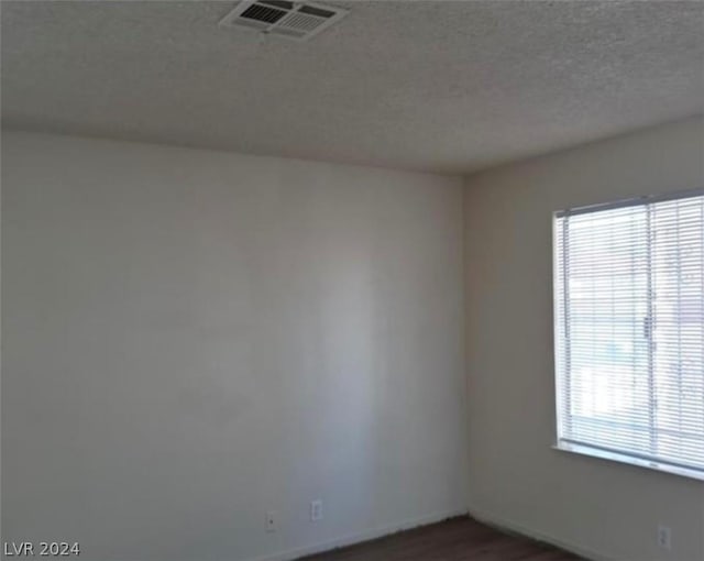 unfurnished room with dark hardwood / wood-style flooring and a textured ceiling