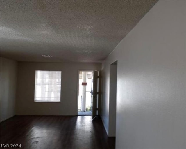 unfurnished room with a textured ceiling and dark hardwood / wood-style flooring