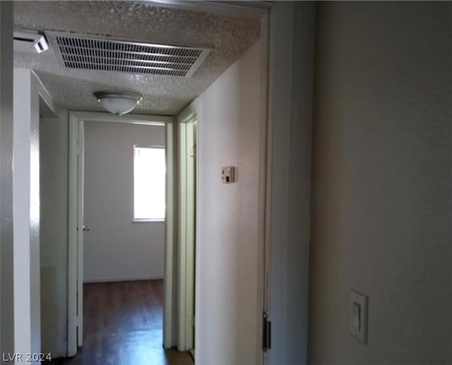 corridor with hardwood / wood-style floors and a textured ceiling