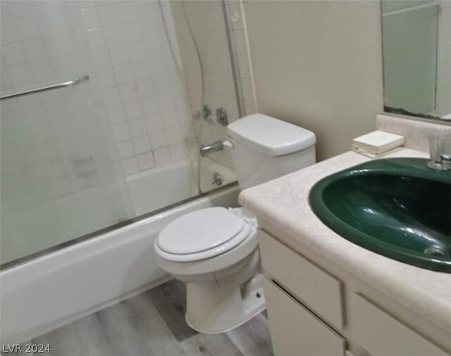 full bathroom with toilet, enclosed tub / shower combo, vanity, and hardwood / wood-style flooring