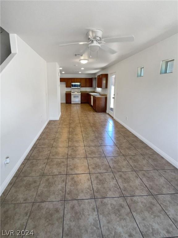 unfurnished living room featuring sink, ceiling fan, and tile floors