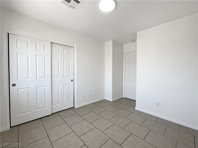 unfurnished bedroom with light tile patterned floors and a closet