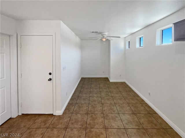 basement featuring ceiling fan and dark tile patterned floors