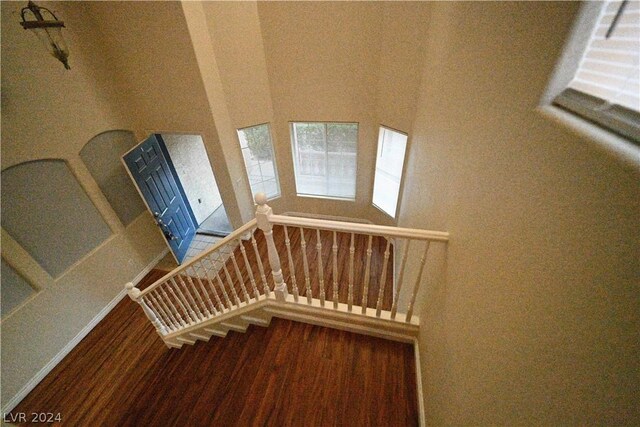 stairway with a towering ceiling and hardwood / wood-style flooring