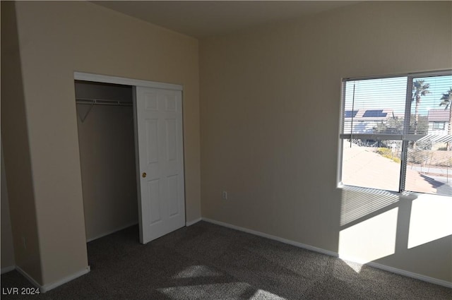 unfurnished bedroom with a closet and dark colored carpet