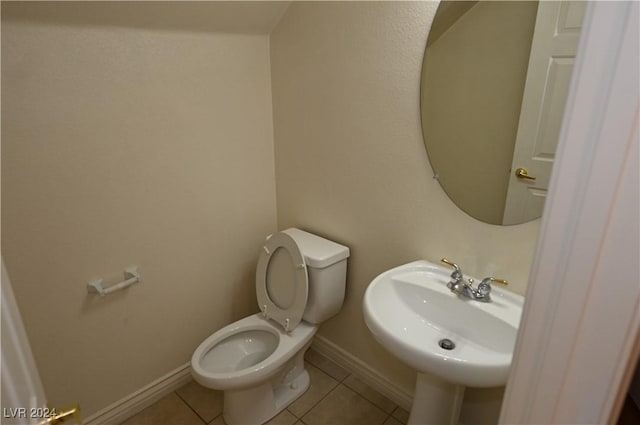 bathroom with toilet, sink, and tile patterned flooring