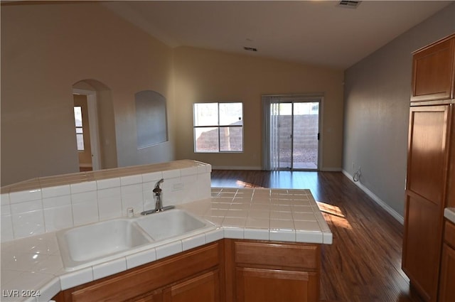 kitchen featuring dark wood-type flooring, sink, tile countertops, and vaulted ceiling