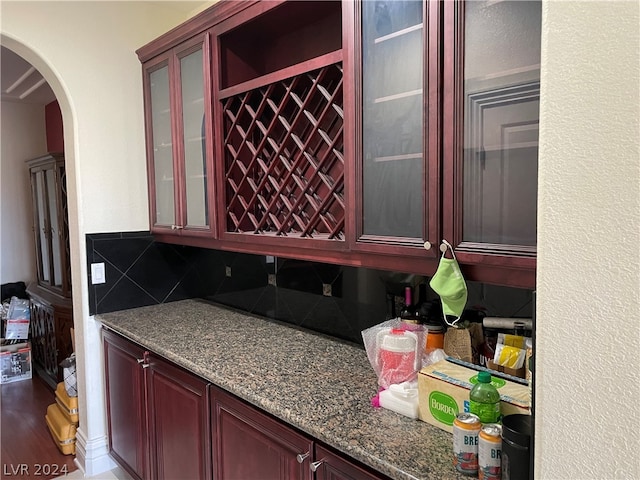 interior space with backsplash, stone counters, and hardwood / wood-style floors