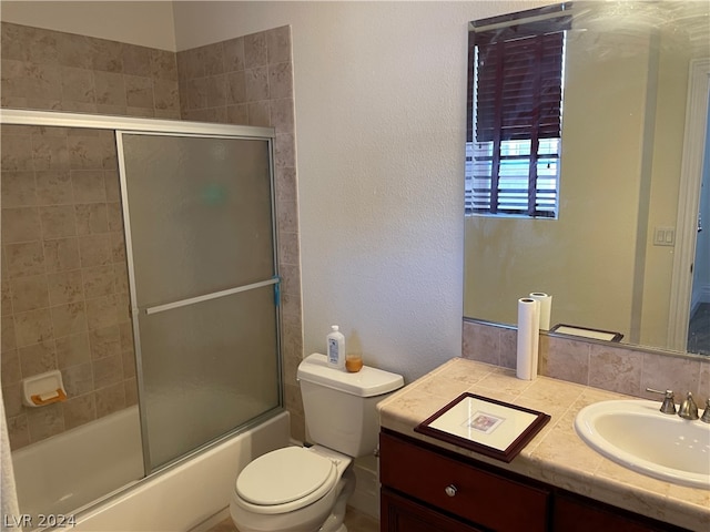 full bathroom featuring shower / bath combination with glass door, vanity, and toilet