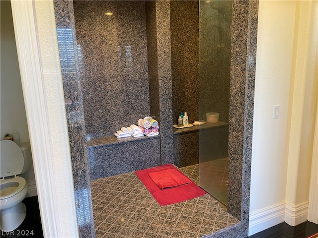 bathroom with tiled shower, tile flooring, and toilet