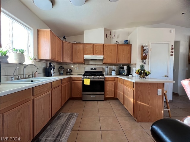 kitchen featuring stainless steel gas range, decorative backsplash, vaulted ceiling, and light tile patterned floors