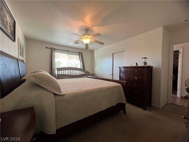 bedroom featuring dark colored carpet, ceiling fan, and a closet