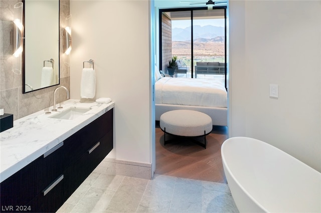 bathroom with ceiling fan, a mountain view, vanity, wood-type flooring, and a tub