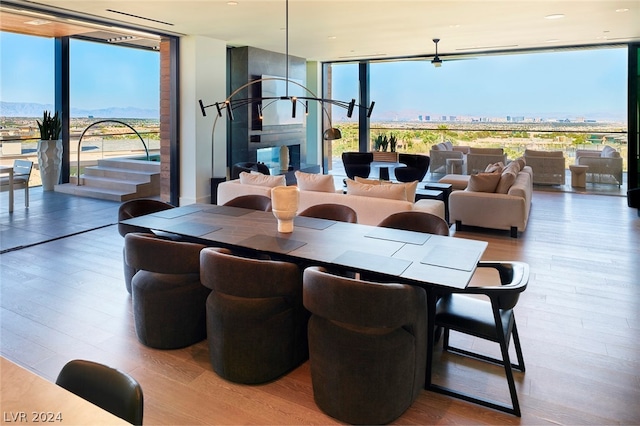 dining room with a fireplace, expansive windows, and hardwood / wood-style flooring