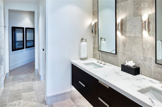 bathroom with dual vanity, tile patterned floors, and tile walls