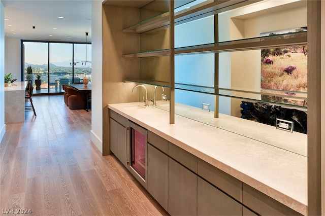 kitchen with sink, a mountain view, floor to ceiling windows, and light wood-type flooring