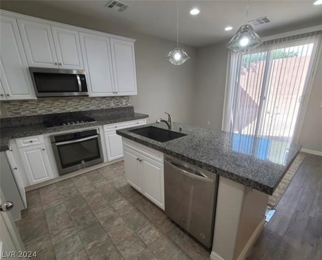 kitchen with white cabinetry, a center island with sink, stainless steel appliances, sink, and tasteful backsplash