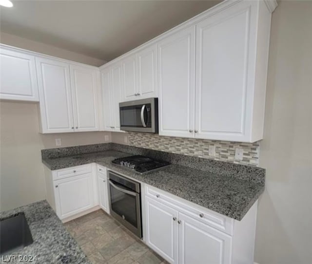 kitchen featuring stainless steel appliances, tasteful backsplash, white cabinets, and light tile flooring