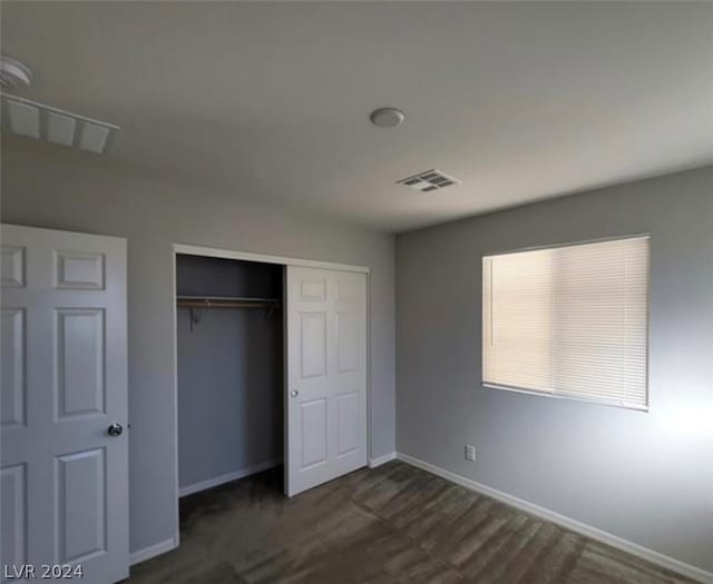 unfurnished bedroom featuring a closet and dark wood-type flooring