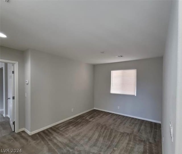 spare room featuring dark colored carpet