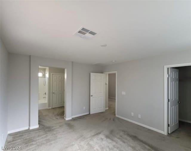 unfurnished bedroom featuring carpet floors, ensuite bath, and a spacious closet